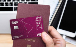uma mão segurando o cartão bradesco smiles visa internacional e um passaporte